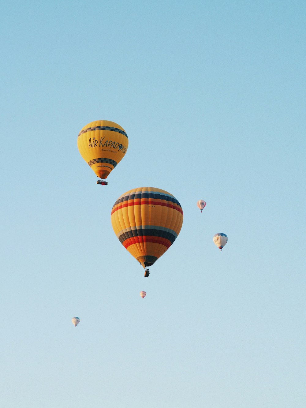 a group of hot air balloons flying through a blue sky