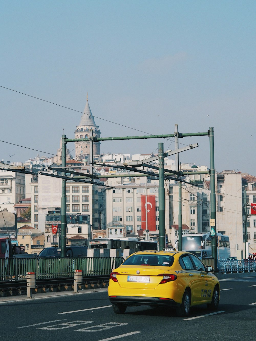 a yellow car driving down a street next to tall buildings