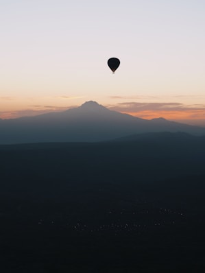 a hot air balloon flying over a mountain range