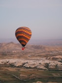 A colorful hot air balloon floating peacefully over rolling hills at dawn.