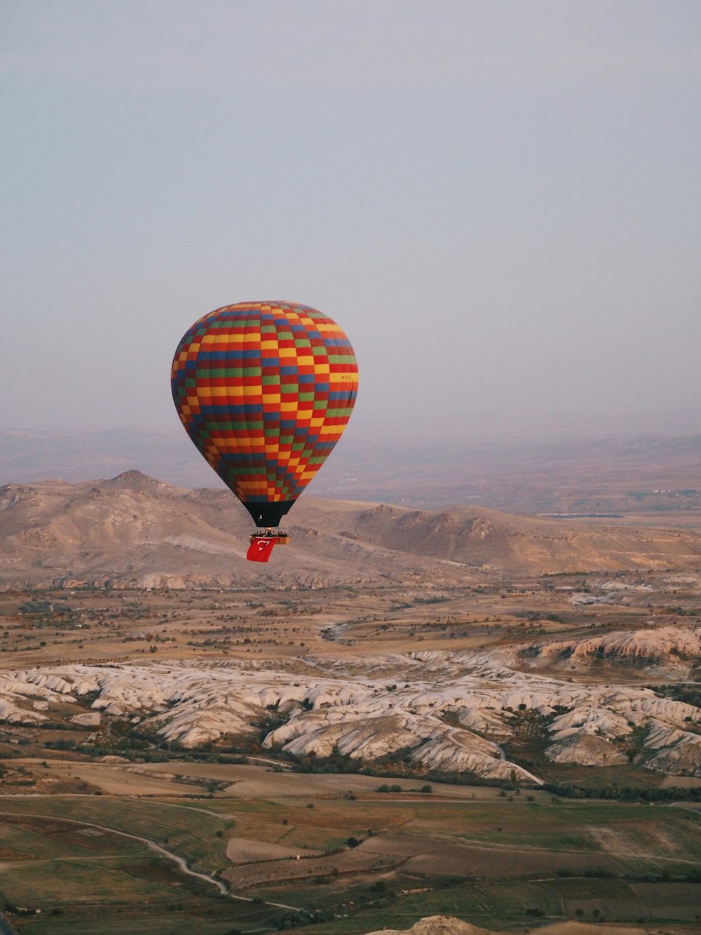 a hot air balloon flying over a valley