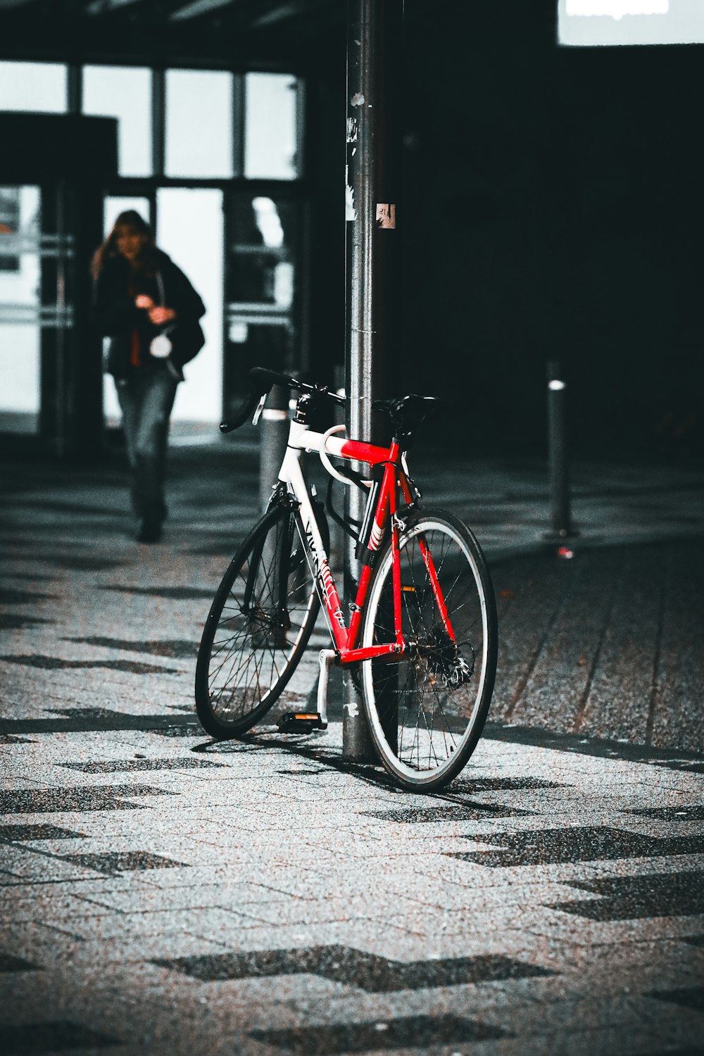 a red bike is leaning against a pole