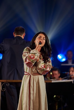 a woman standing on a stage singing into a microphone