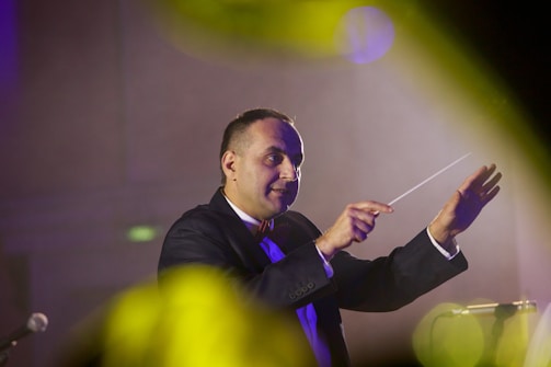 a man in a suit and tie holding a conductor's baton