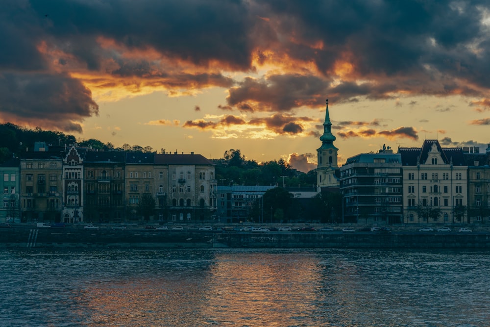 a sunset over a city with a church steeple in the distance