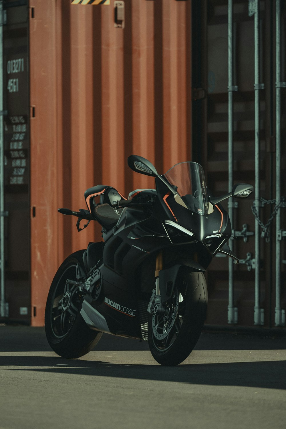 a black motorcycle parked in front of a shipping container