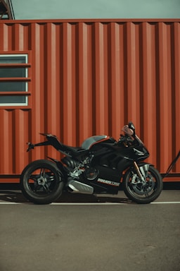 A sleek motorcycle parked in front of a red and black garage, reflecting the brand colors.