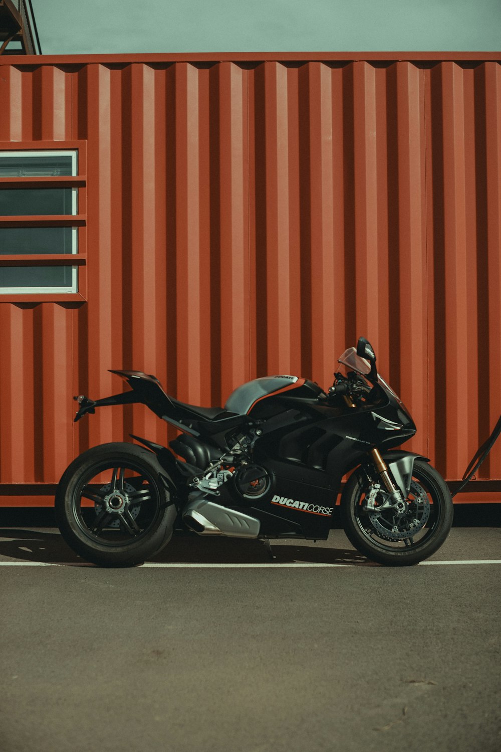 a black motorcycle parked in front of a red shipping container