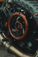 Close-up view of a motorcycle engine with a focus on the detailed components and branding. The metallic parts, including a prominently featured red circle marked with 'Special Parts' and 'Made in Italy', are contrasted with dark mechanical textures. Various elements like pipes and gears exhibit intricate design, reflecting craftsmanship and engineering.