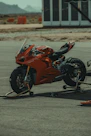 a red motorcycle parked on top of a parking lot