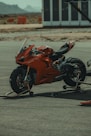 a red motorcycle parked on top of a parking lot