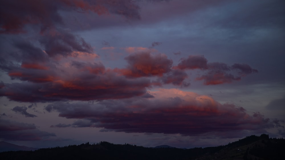 the sky is filled with pink clouds as the sun sets