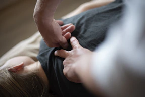 Hands pressing into the back of a person wearing a black shirt