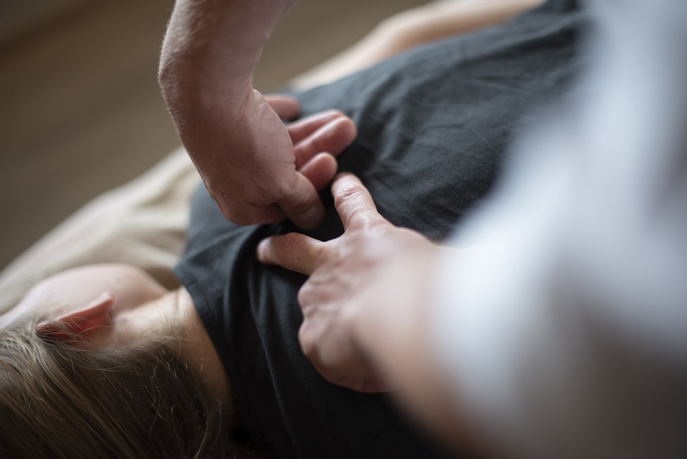 uma mulher deitada em cima de uma cama segurando a mão de um homem