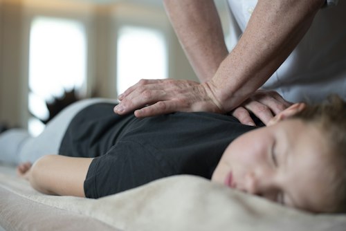 Chiropractor's hand technique on a relaxed patient's shoulder and upper back