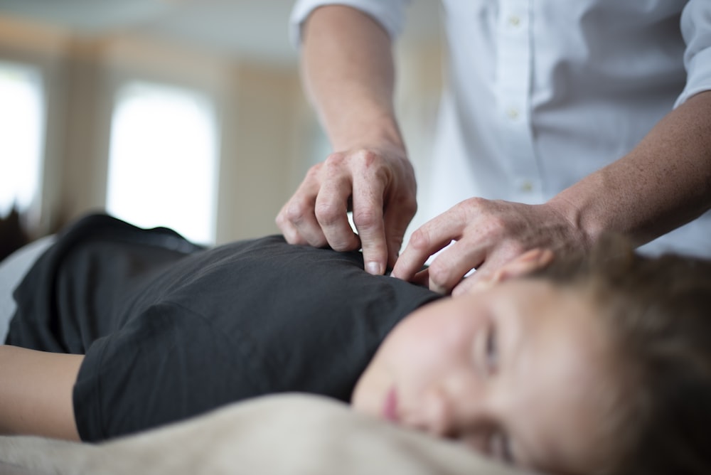 uma mulher recebendo uma massagem de um homem em uma camisa branca