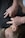 Hands appear to be performing a massage technique on a person's back, with fingers pressing into the back near the shoulders. The person receiving the massage is laying on a soft surface with their face turned to the side.
