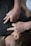 A person wearing a dark shirt is lying down, while another person's hands are pressing on their back or chest area. This seems to be either a massage or a therapy session.