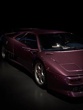 A sleek black car being detailed outdoors with vibrant purple accents in the background.