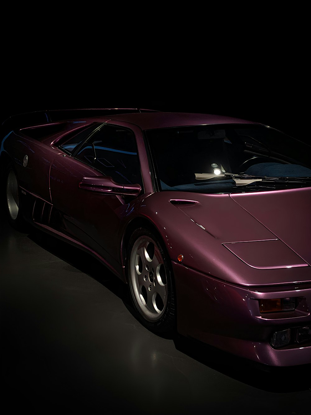 a purple sports car in a dark room