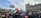 A large group of people gathered in a protest outside an ornate building, holding flags and signs with messages of support for Palestine. The crowd appears diverse, with many individuals facing the building, contributing to a sense of unity and determination.