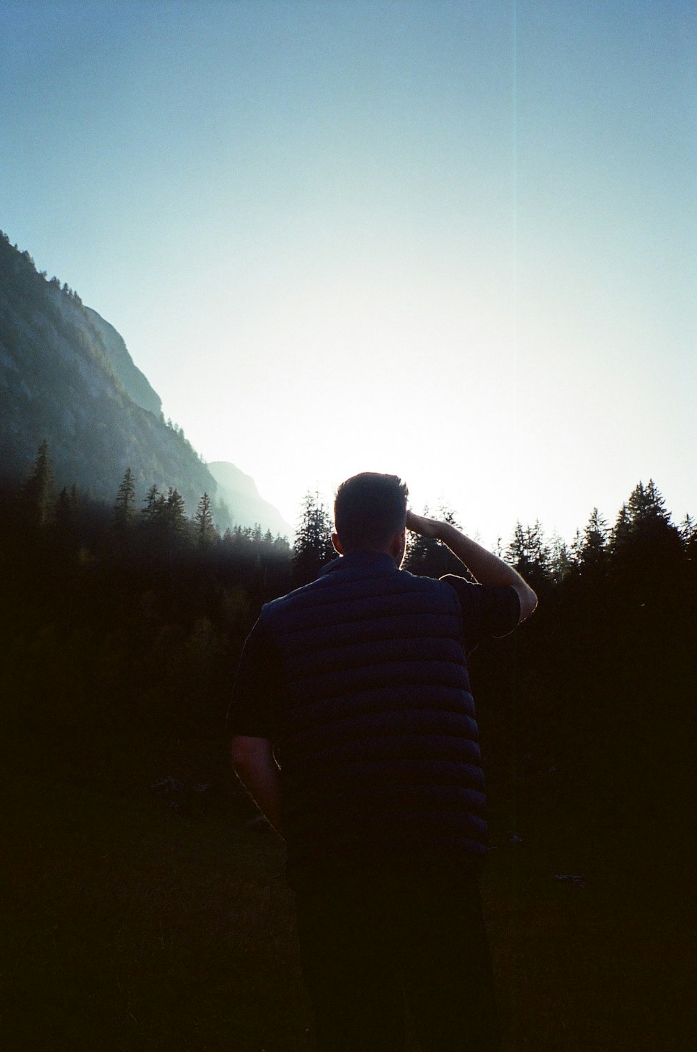 a man standing in a field looking at the sun