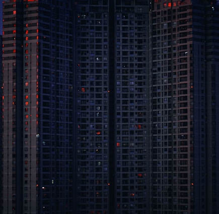 A fortified apartment complex with red neon accents and surveillance cameras glaring in the night.