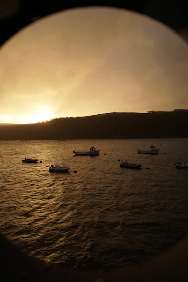 Sunset over Cádiz bay with colorful boats gently floating near the shore.