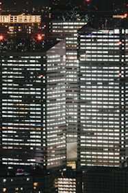 A crisp, ultra-modern cityscape at night with sharp lines and contrasting black, grey, and bright red lighting.