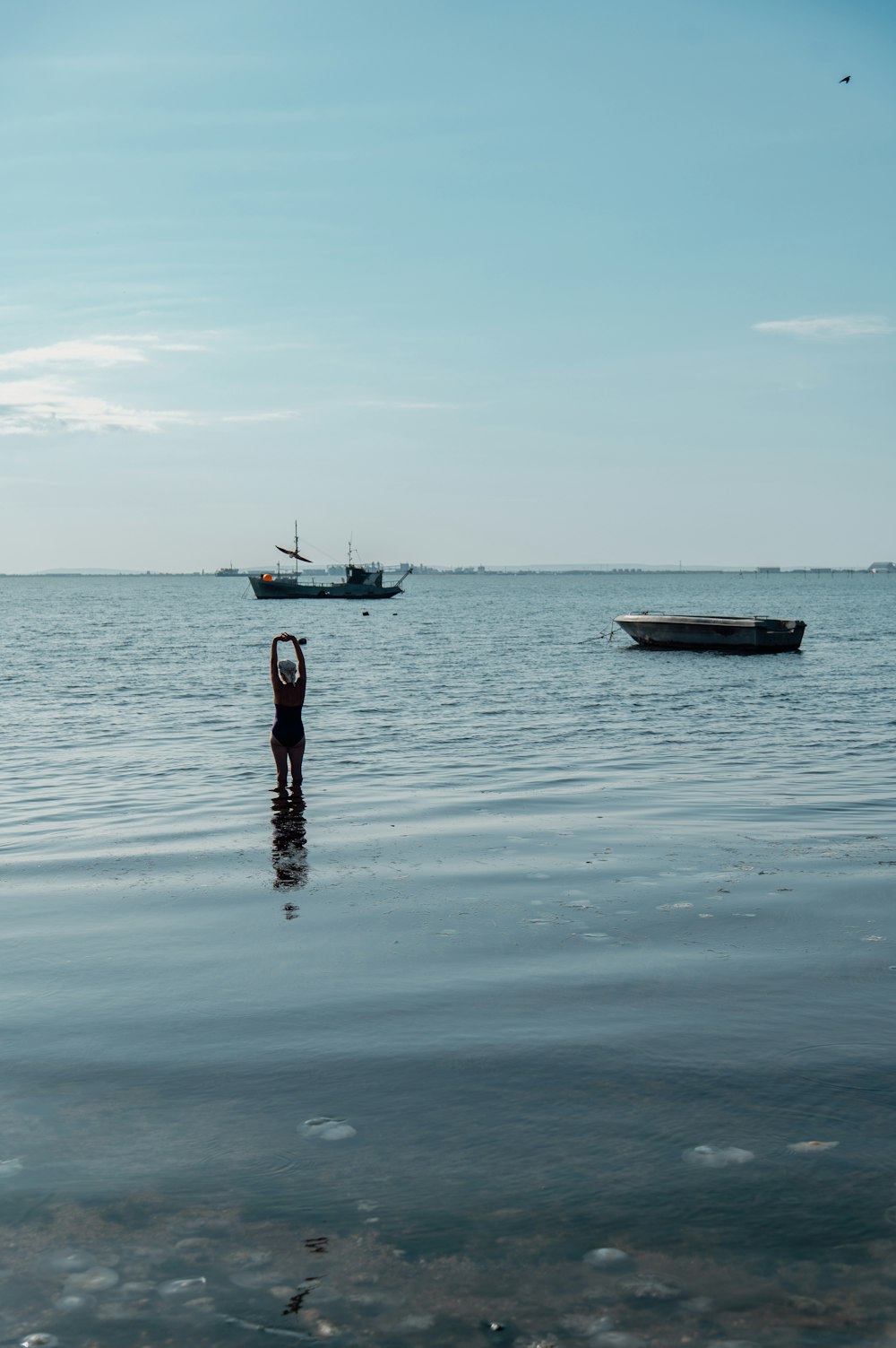 a person standing in the water with a boat in the background