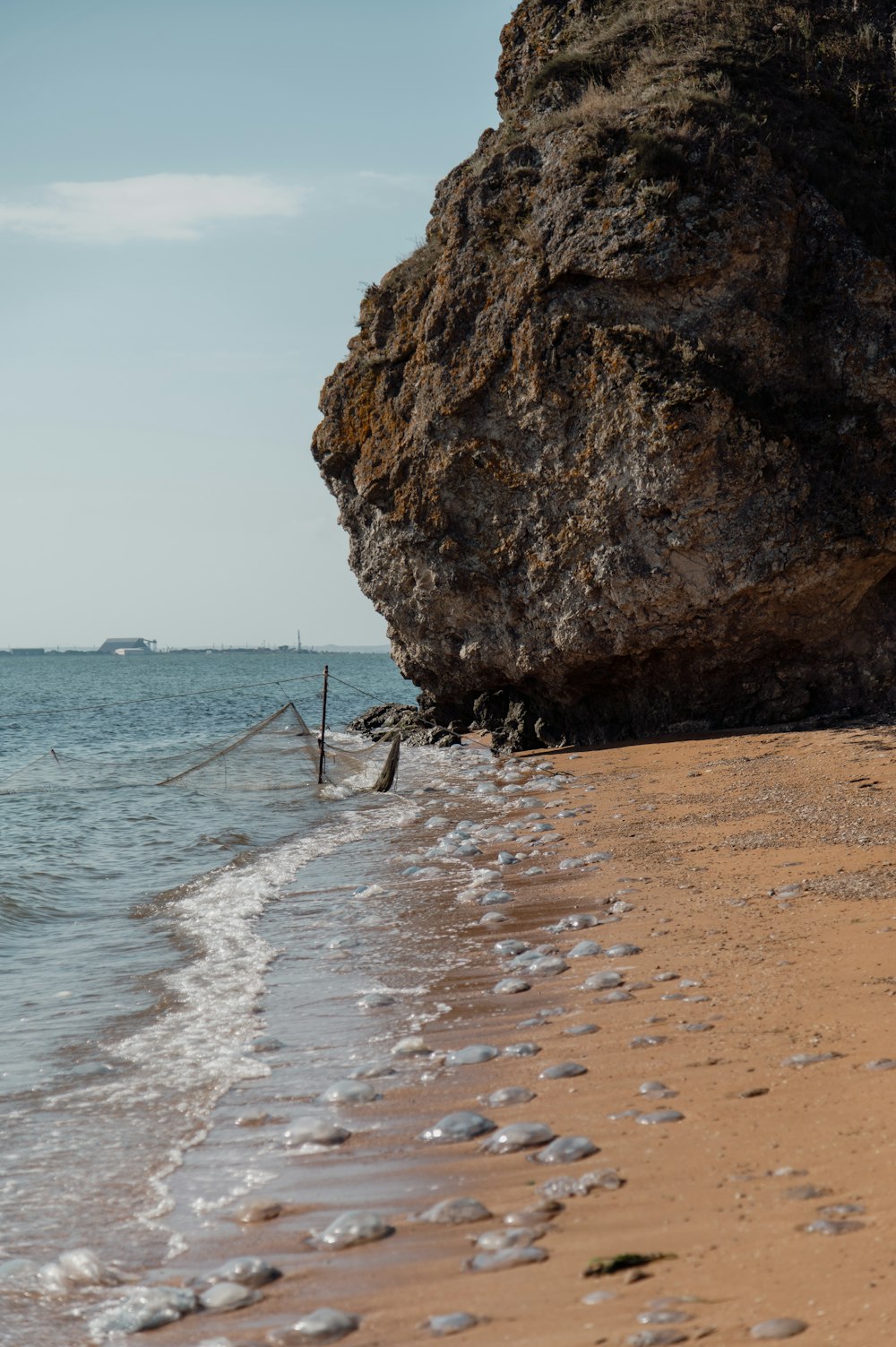 a rock sticking out of the ocean next to a beach