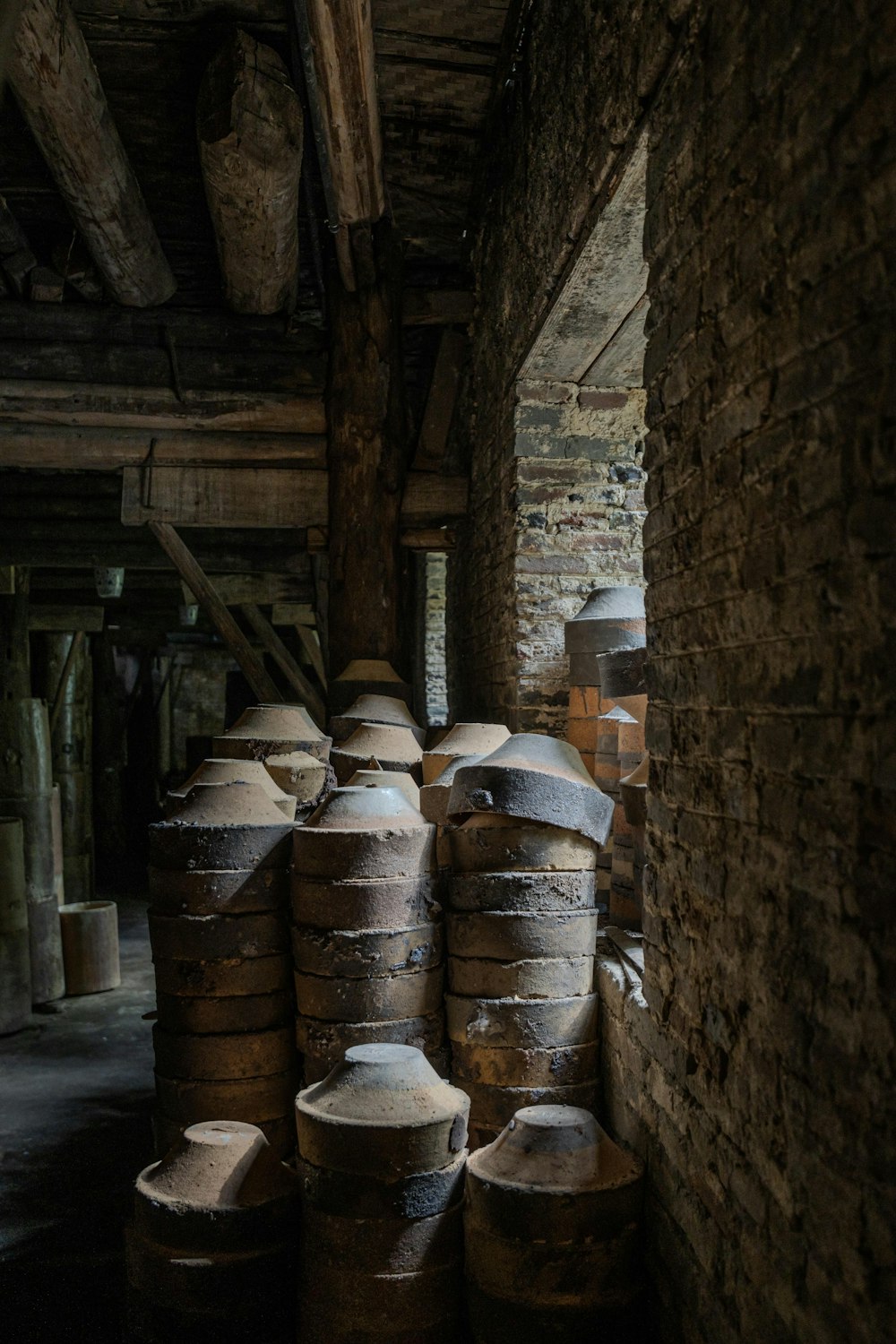 a room filled with lots of barrels next to a brick wall