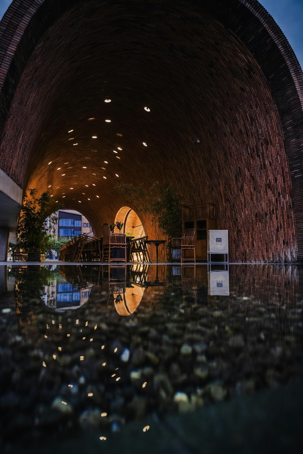 a tunnel with a reflection of a building in the water