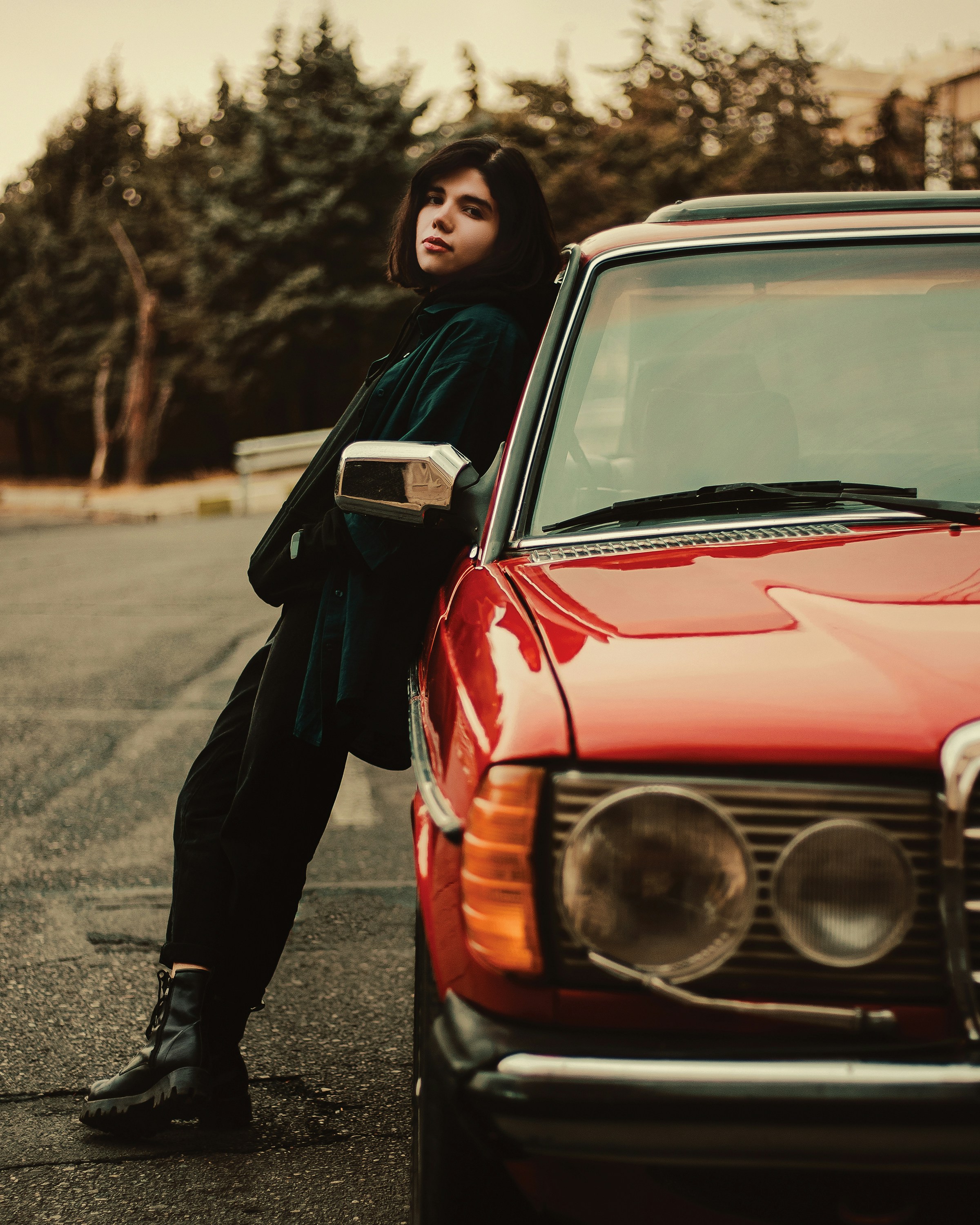 a woman leaning on the hood of a red car