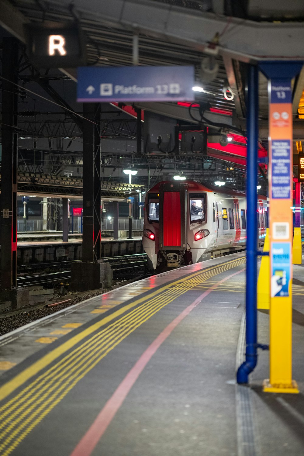 un train qui entre dans une gare la nuit