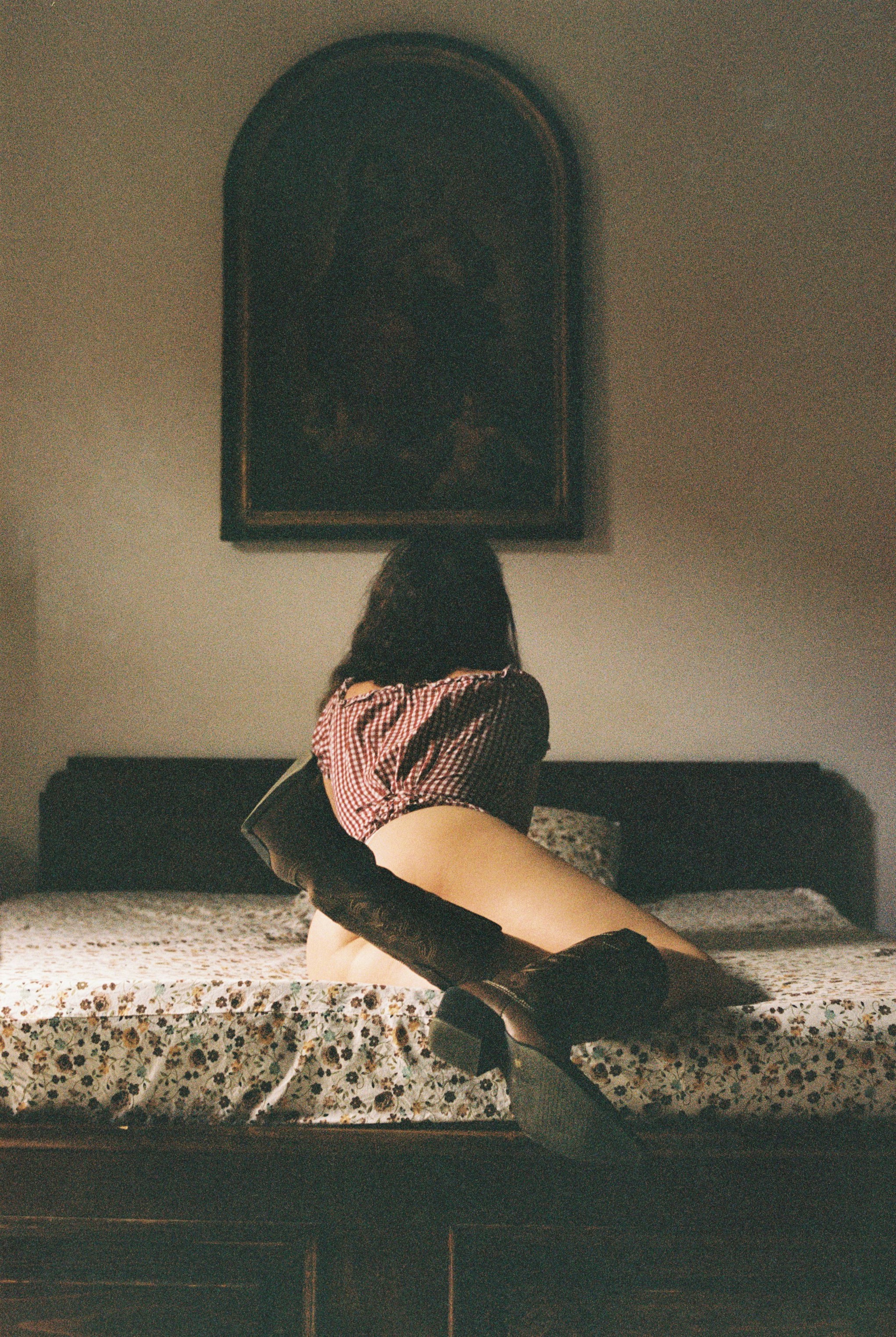 a woman sitting on top of a bed next to a painting
