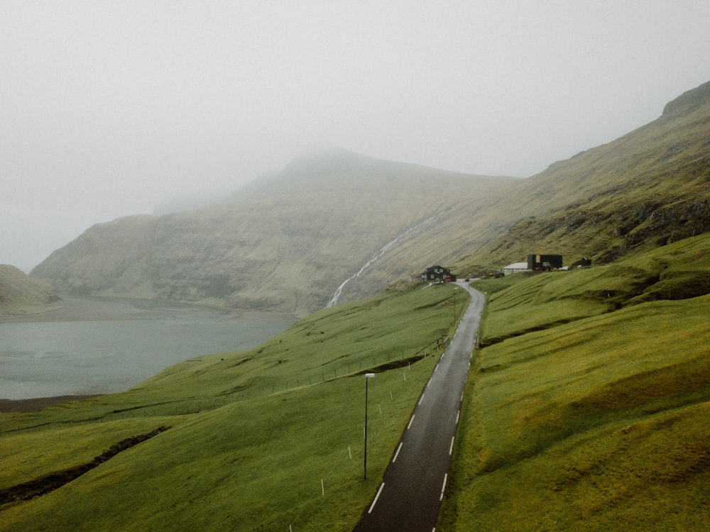 a road going down a hill with a body of water in the distance