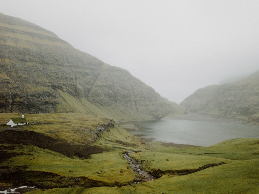 a foggy day in a valley with a small house