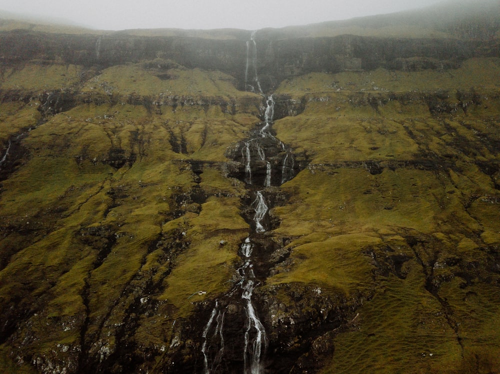 a very tall waterfall in the middle of a lush green hillside