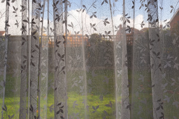 Elegant sheer curtains gently billowing by an open window with a garden view.