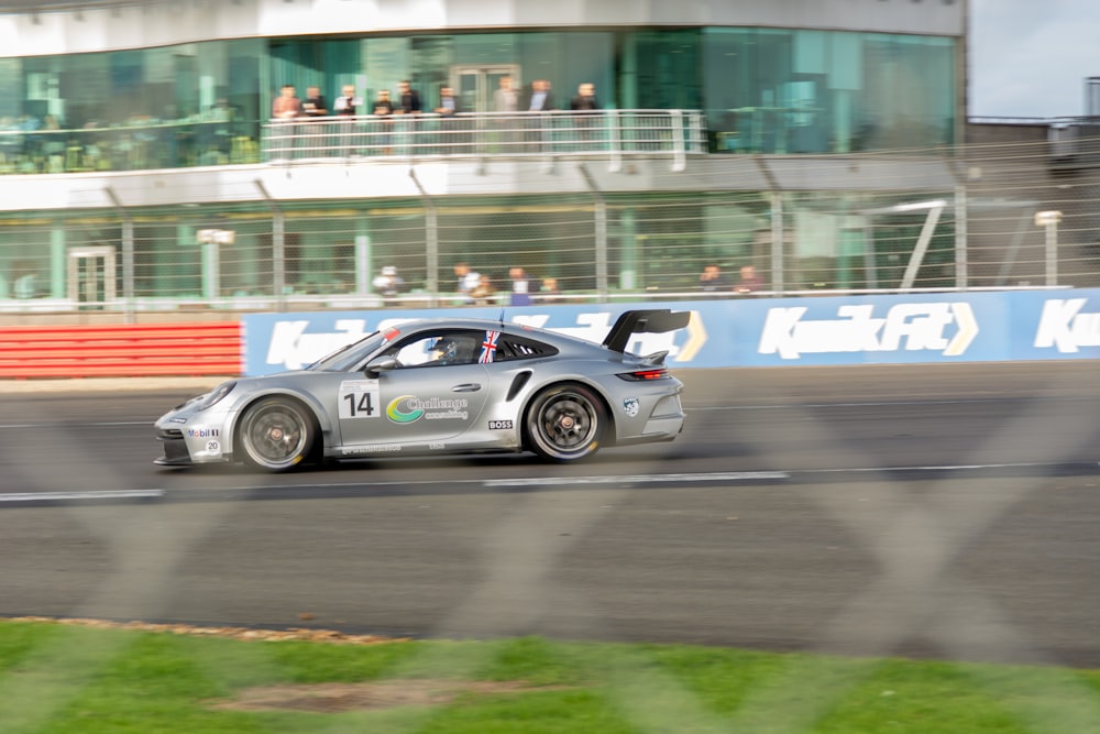 a silver car driving down a race track