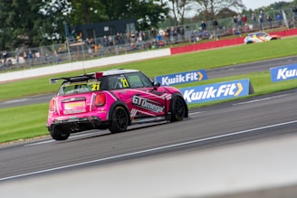 A close-up shot of a pink pastel race car speeding on a track under a clear sky.