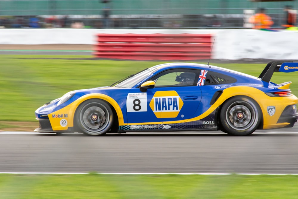 a blue and yellow race car driving on a track