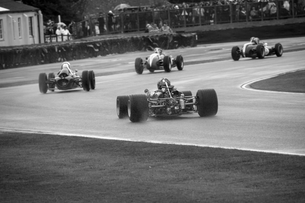 a black and white photo of three racing cars