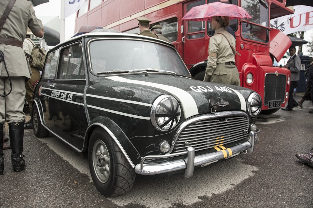 a black and white car parked next to a red double decker bus