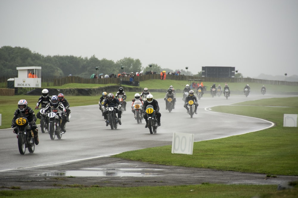 a group of people riding motorcycles down a wet road