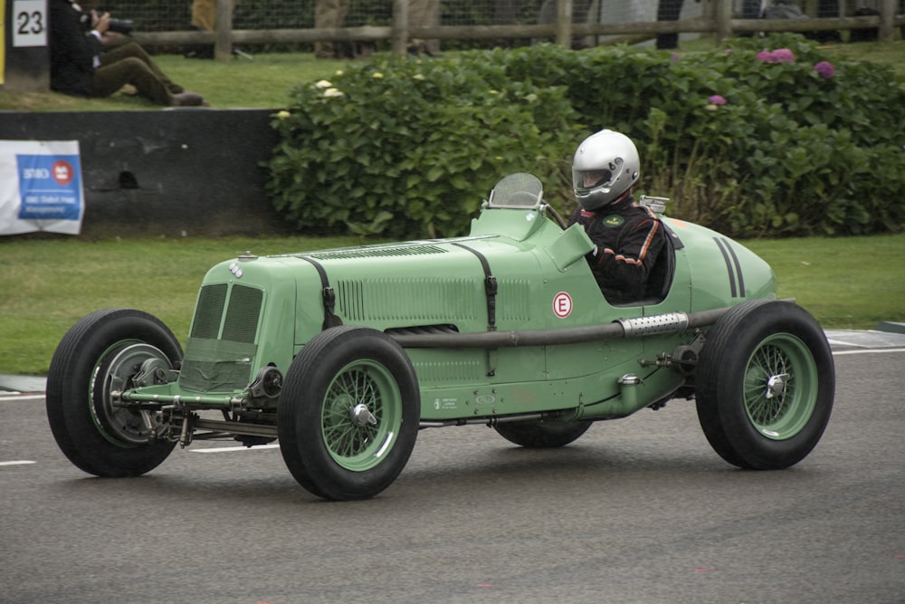 a man driving a green race car down a street