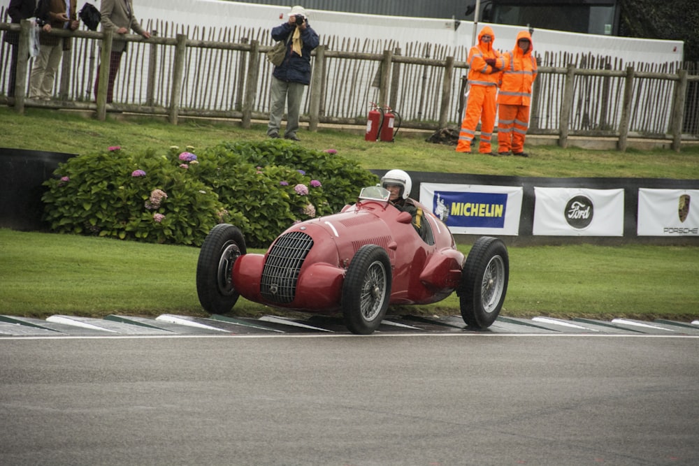 a man driving a red race car down a race track