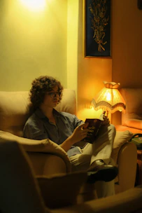 A person happily reading an e-book on a tablet in a comfortable armchair.