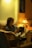 A person reading a book in a cozy chair with a warm light.